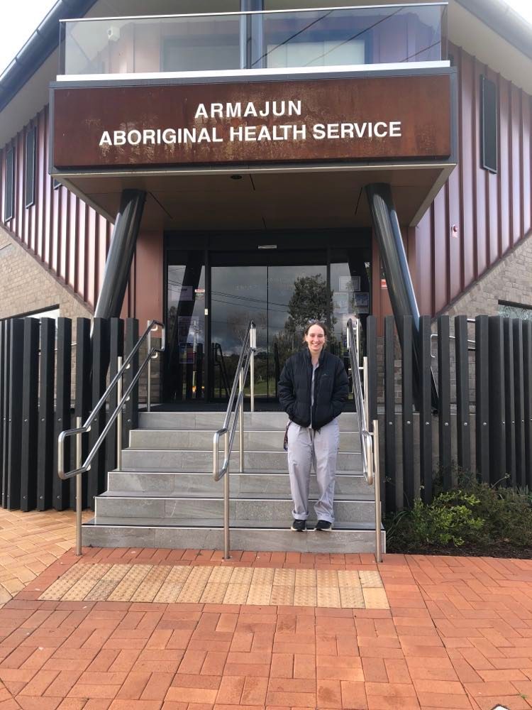 Young female medical student standing in front of an Aboriginal Health Service Centre for a photo