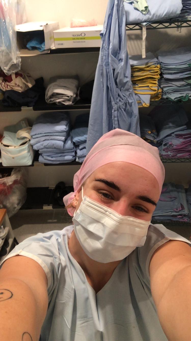 Young woman in medical scrubs and cap takes a selfie in a hospital room