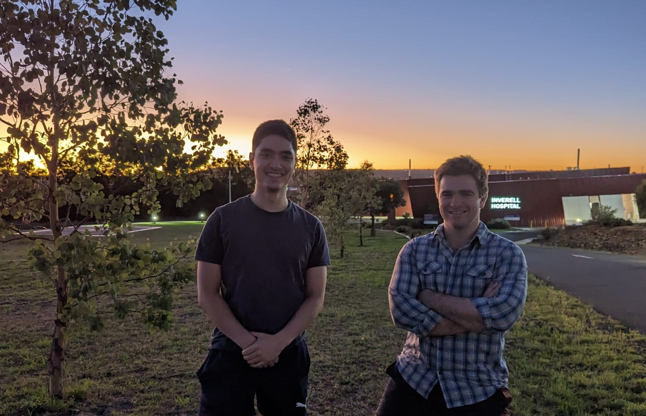 Two young man pose for a photo outside a country hospital