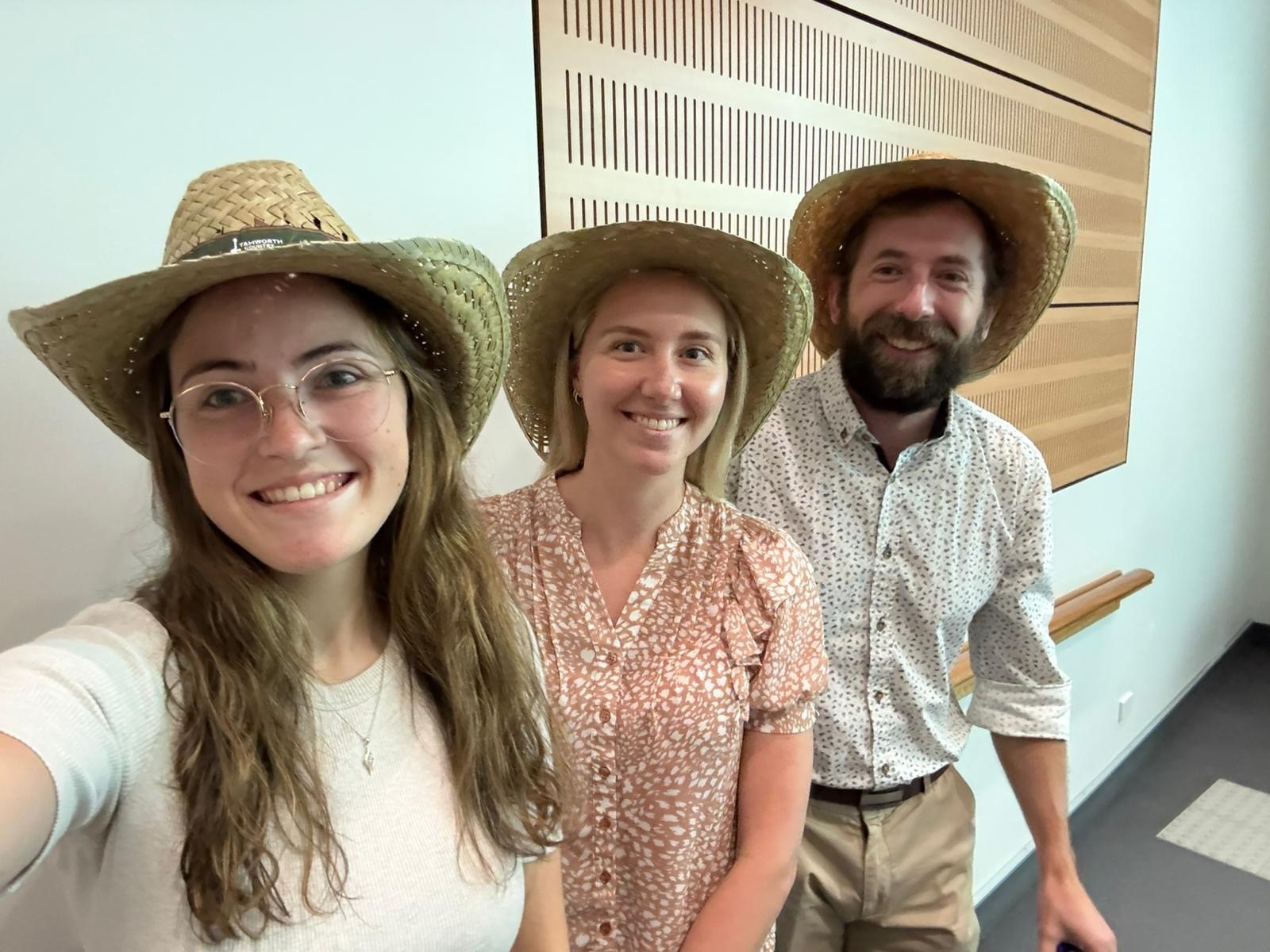 Two female and one male medical students in plain clothes and straw brim hats pose for a photo.