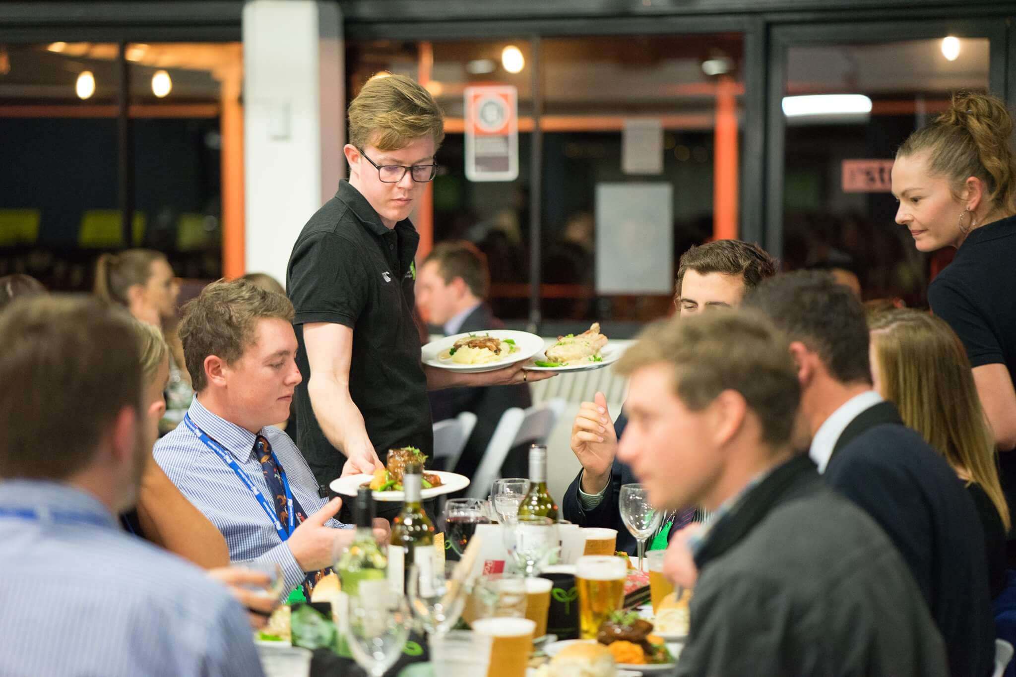 Waiter serves dinner to a table of students