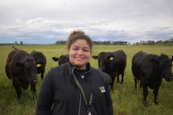 woman standing in a field with cattle in the background.