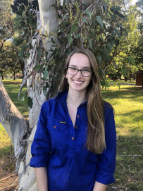 Head shot of a woman standing in front of a tree
