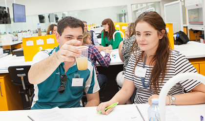 Two university students examining a liquid in a cup.