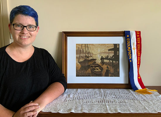 Dr Mary McMillan with a painting of boats draped with a champion ribbon from the New England Show 