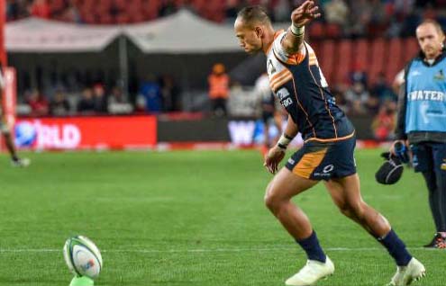 Australian rugby star Christian Leali'ifano kicks a football as UNE's Dr Ben Serpell appears in the background, watching on from behind.