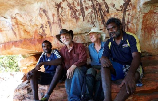 A woman and three men (two Indigenous brothers) sitting in a cave.