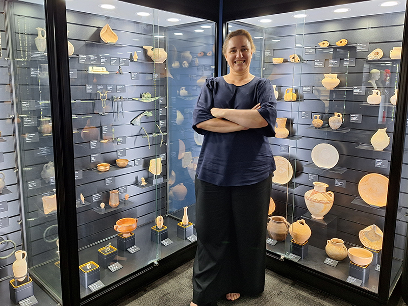 Bronwyn Hopwood stands in front of the new cabinets wdisplaying the Classics collections in the UNE Museum of Antiquities 