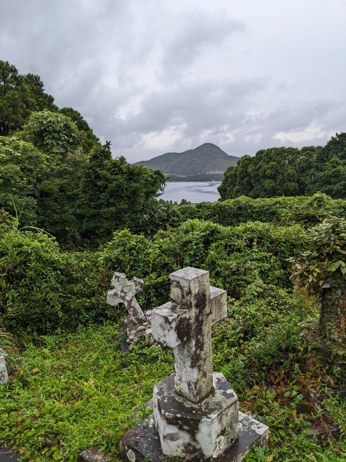 Stone crosses mark graves on a forested hillside.