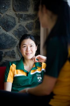 Close up of female student in Mary White College shirt, listening intently to another student