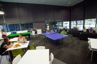 Study room with students in groups at desks, and in a lounge area.