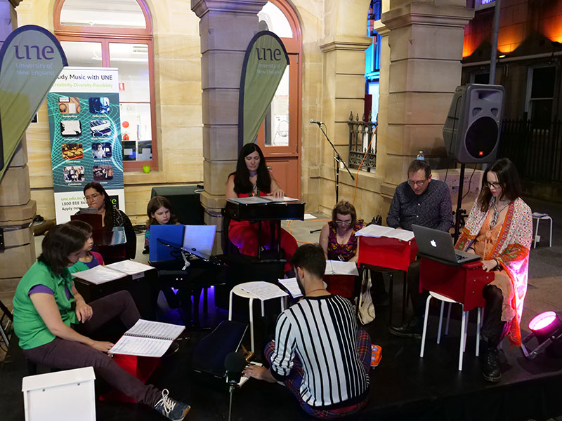 A group of people with toy pianos, working on the floor.