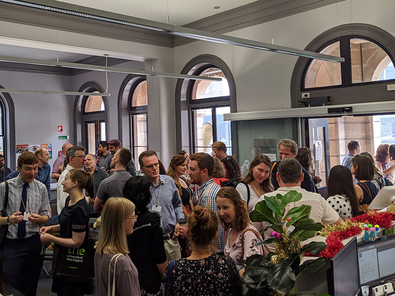 Seminar room at UNE Sydney with two speakers and a large audience group