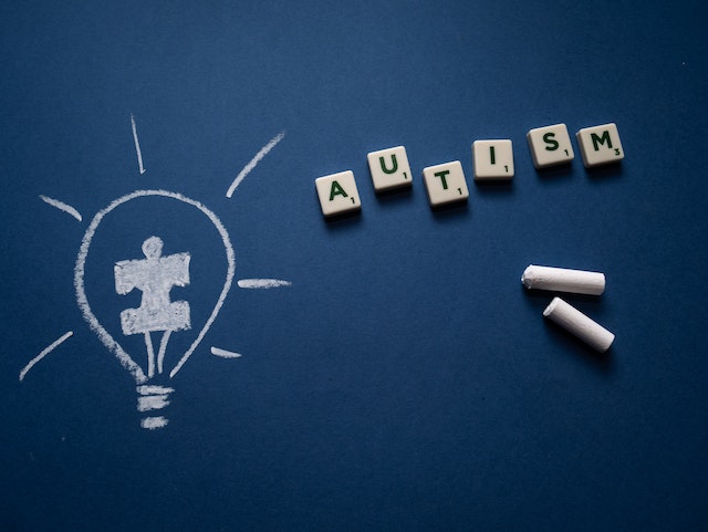 Drawing of light bulb with puzzle piece inside, letters spelling autism