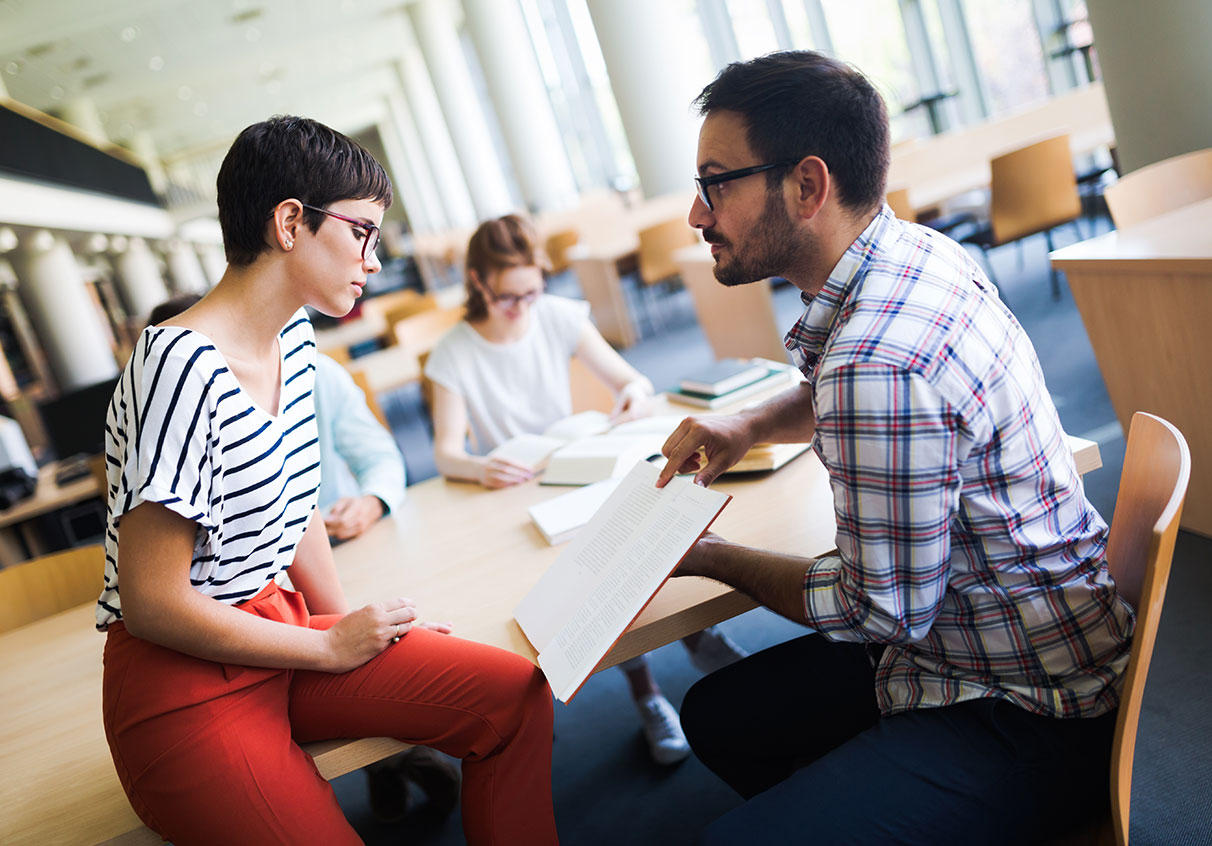Male and female students working together on their course work in a library..