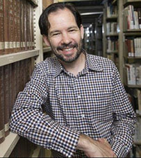 Casual portrait image of Gwyn McClelland leaning on a library shelf 