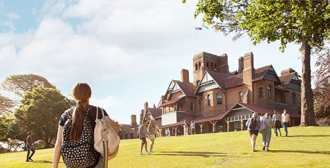 University campus with students on a sunny day, historic brick building and green lawn