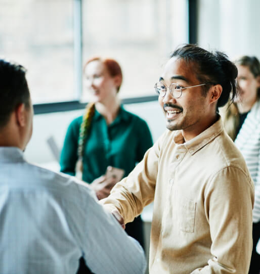 A man receiving a handshake, surrounding by a group of people. 